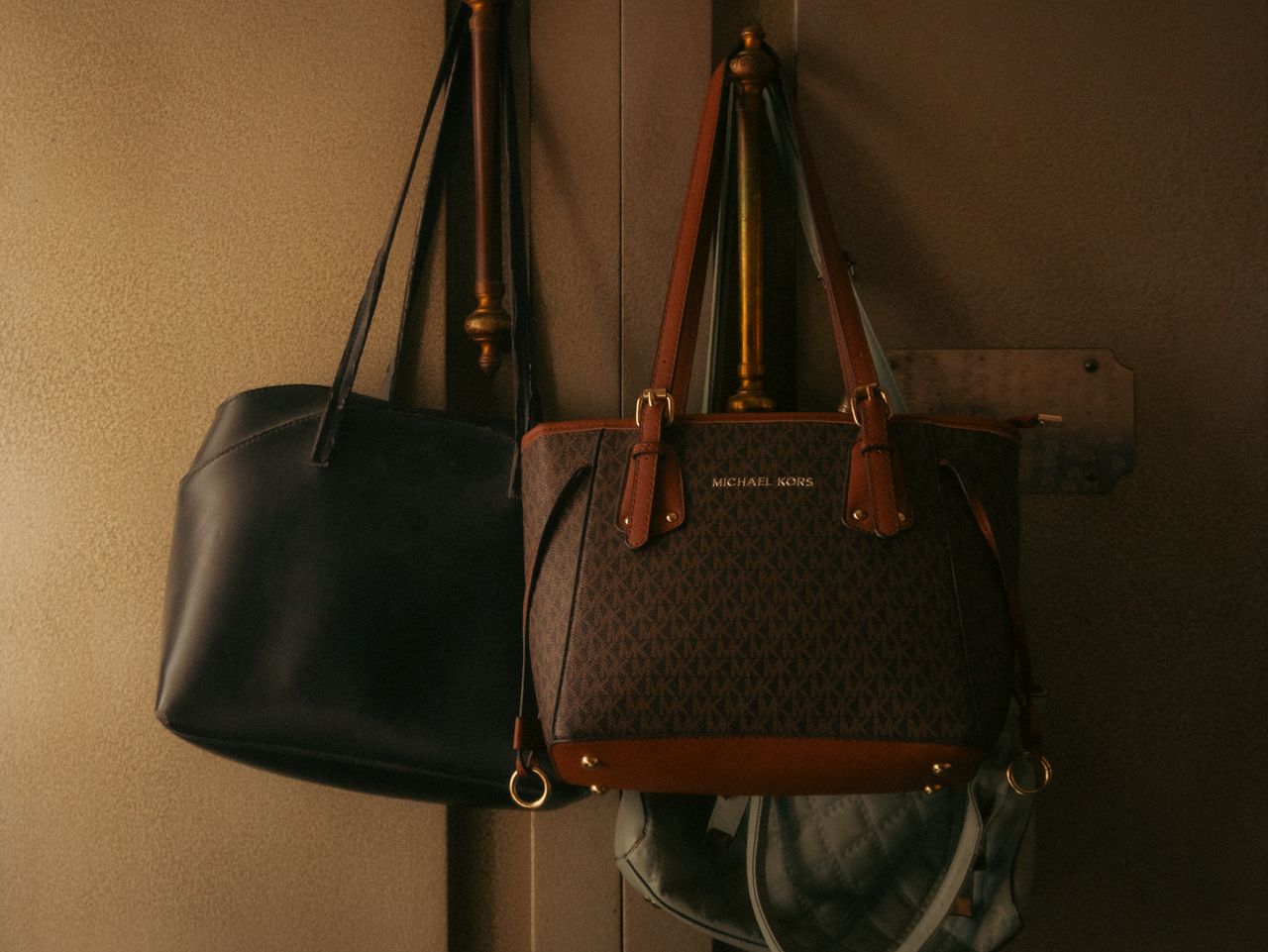 Stylish leather handbags hanging on a wall hook, showcasing elegant design and rich tones.